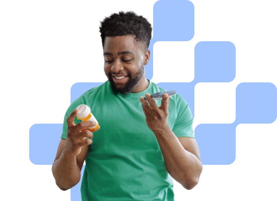 man smiling holding his phone and looking at a medication bottle